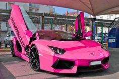 a pink sports car parked in front of a bus stop