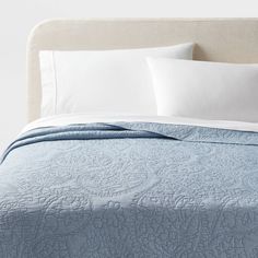 a bed with white pillows and blue quilted bedspread on top of it