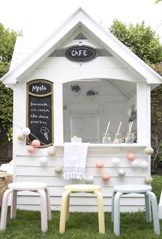 an outdoor cafe with two chairs and a chalkboard sign