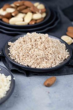 nuts and rice in black plates on a table with other food items around them,