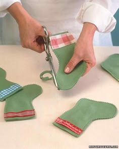 a person cutting fabric with scissors on top of a white table and some green mitts