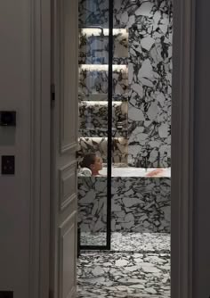 an open door leading to a bathroom with black and white marble tiles on the walls