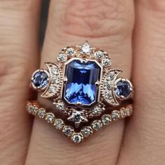 a woman's engagement ring with an oval blue sapphire surrounded by smaller round diamonds