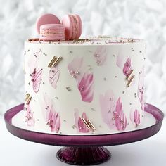 a white cake with pink frosting and macaroons on top