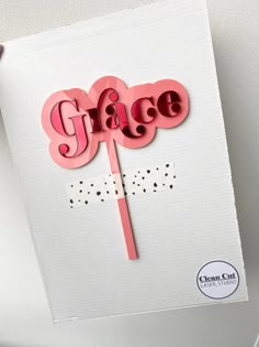 a pink cake topper with the word grace on it and an arrow in the middle