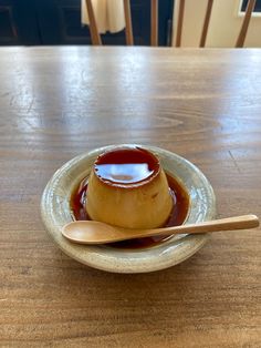 a wooden table topped with a small bowl filled with sauce and a spoon next to it