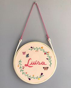 a wall hanging sign with the word lusa painted on it and butterflies around it