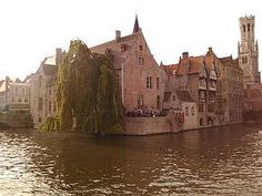 an old building sitting on the side of a river next to tall buildings with towers