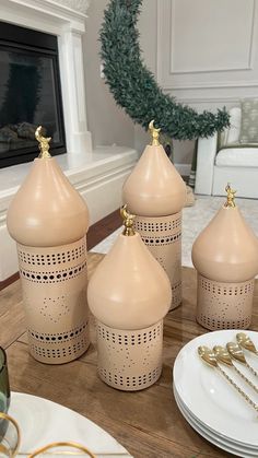 three vases sitting on top of a wooden table next to plates and forks in front of a fireplace