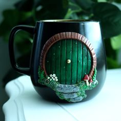 a black coffee mug with a green door painted on it