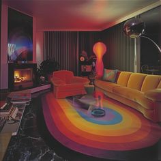 a living room filled with furniture and a rainbow rug on the floor in front of a fire place