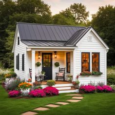 a small white house with flowers in the front yard