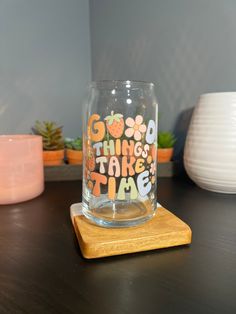 a glass with the words go good things take time on it sitting on a wooden coaster