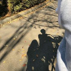 the shadow of a person riding a bike on a road with leaves all over it