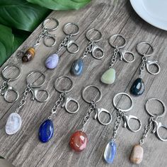 a bunch of different colored stones are on a table next to a white plate and green leaves