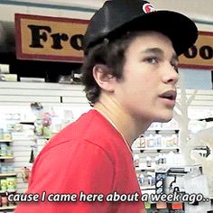 a young man wearing a black hat and red shirt is talking to someone in the store