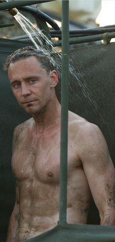 a shirtless man is standing under a shower in the rain with no shirt on