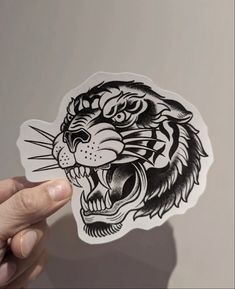 a hand holding up a sticker with a tiger's head in the middle