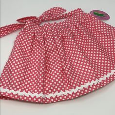 a red and white polka dot dress with a bow at the waist, sitting on a table