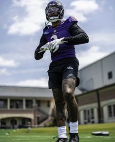 a football player is running on the field with his hands in the air while wearing a helmet and gloves