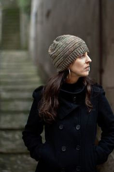 a woman wearing a hat and coat standing in an alleyway