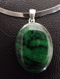 "Large Transvaal Jade stone set in sterling silver pendant. The stone is a dark green with darker stratification. The pendant is 1.5 inches long without the bail; with bail, it measures 1.8 inches. The pendant comes with a sterling silver stiff collar necklace. The necklace is 5.5 inches long and 4.5 inches wide. it has 2.6 inch gap so it can be easily put on or taken off. The collar has a maker's mark and is marked \"925\" and \"Mexico\". The collar can be worn with or without the pendant." Green Pendant Gemstones For Formal Occasions, Green Cabochon Oval Pendant Necklace, Green Oval Necklace With Large Stone, Oval Green Necklace With Large Stone, Green Jewelry With Large Stone In Round Pendant, Green Oval Pendant Jewelry With Large Pendant, Hallmarked Green Pendant Gemstones, Green Sterling Silver Pendant Gemstone, Sterling Silver Necklace With Large Green Stone