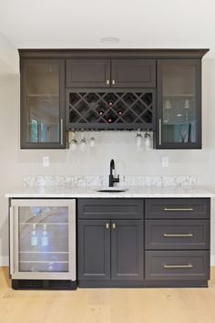 a kitchen with gray cabinets and marble counter tops, wine rack on the wall above the sink