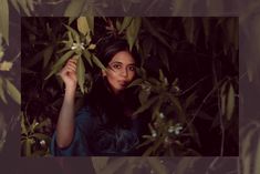 a woman is standing in the middle of some plants and looking at the camera with an intense look on her face