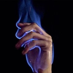 a close up of a person's hand holding something with blue light coming out of it