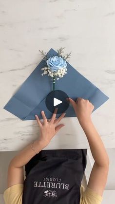 a woman holding up a blue envelope with a flower on it and the word prodile written in white