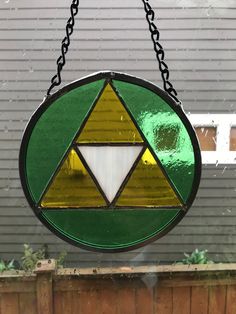 a green and yellow stained glass window hanging from a chain on a house's front door