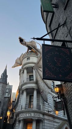 a dragon statue on the side of a building in front of a clock and sign