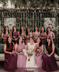 the bride and her bridal party pose for a photo in front of an outdoor wall