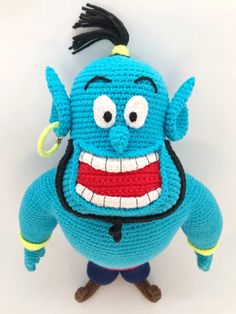 a crocheted blue stuffed toy with an evil smile on it's face