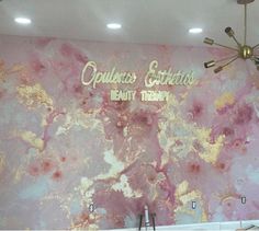 a pink and gold painted wall with chandelier hanging from it's ceiling