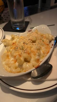 a white plate topped with macaroni and cheese next to a glass of water