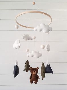 a teddy bear is hanging from a wooden wind chime with snow and trees on it