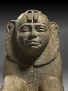 an ancient statue with a face on it's head