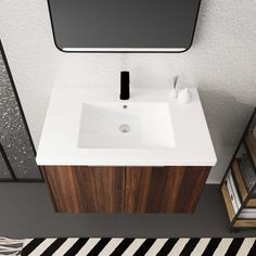 a white sink sitting under a mirror next to a black and white striped floor rug