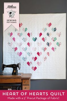 a sewing machine sitting next to a quilt on top of a wooden table with the words heart of hearts quilt