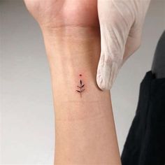 a woman's wrist with a small tattoo on the left side of her arm