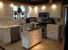 a large kitchen with white cabinets and stainless steel appliances, including an island in the middle