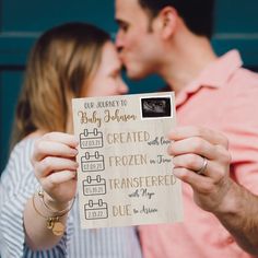 a man and woman kissing while holding up a sign