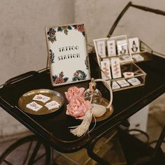 a table topped with cards and flowers on top of a wooden table next to a metal tray