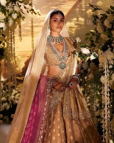 a woman wearing a bridal gown and jewelry in front of a floral display with flowers