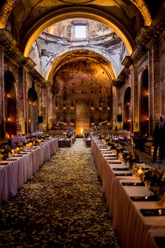 a long table is set up in the middle of an old building for a formal function