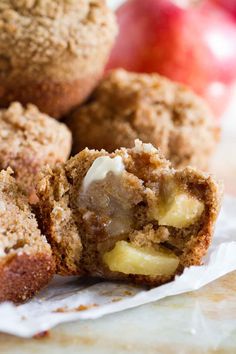 an apple muffin cut in half on top of a napkin next to some apples