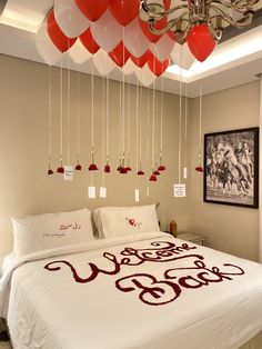 a bed with red and white balloons hanging from the ceiling