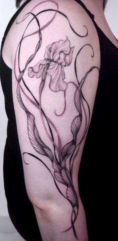 a woman's arm with flowers and leaves on the back of her shoulder, which is