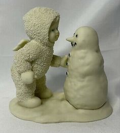 a small statue of a man and a snowman are touching each other's hands